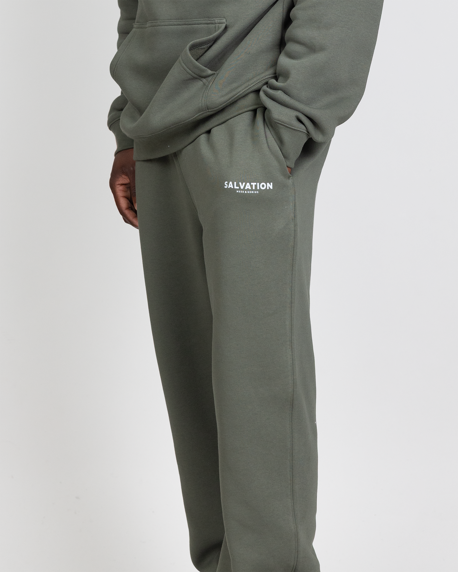 Faith-inspired track pants in army green featuring Salvation text logo, jersey lined pockets, and clean streetwear style.